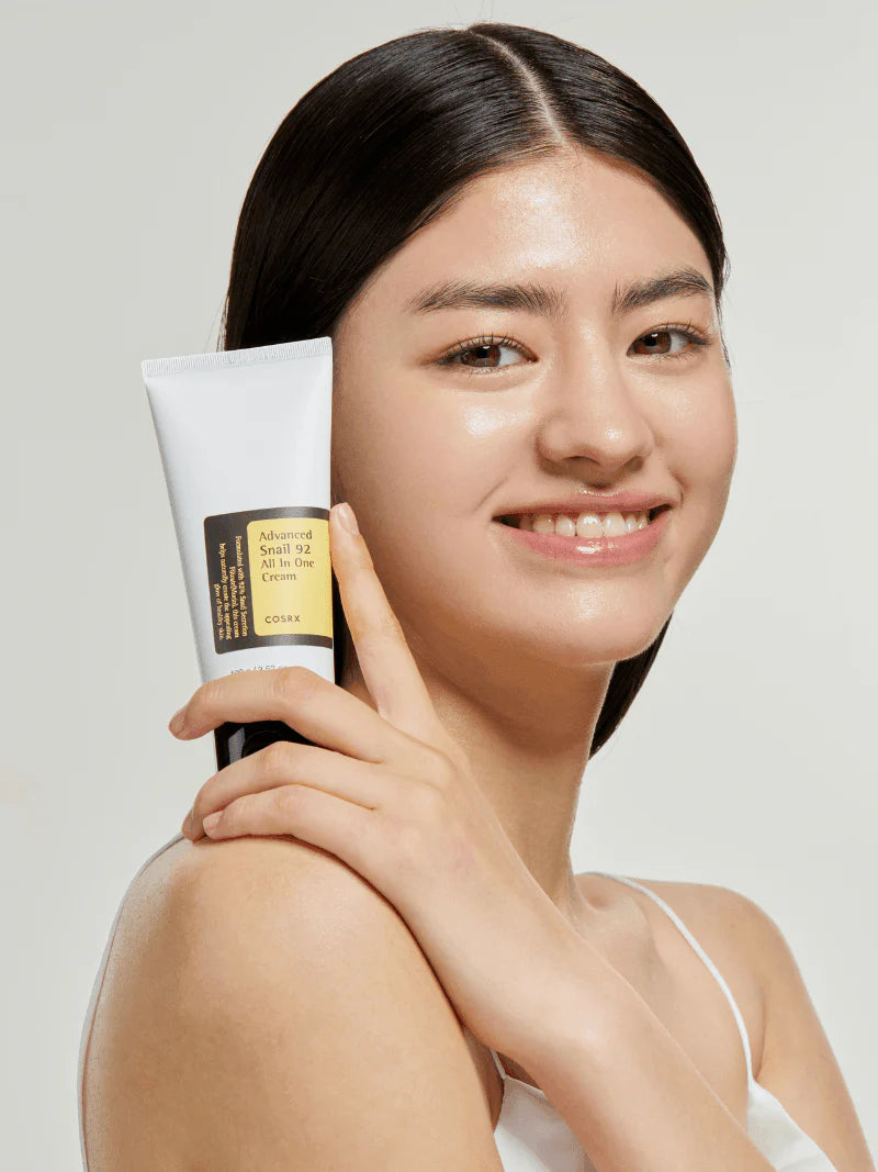 Woman holding COSRX Advanced Snail 92 All in One Cream tube – Korean skincare moisturizer